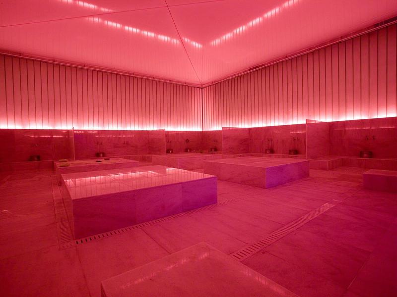 Moderne sauna met rode verlichting, houten banken en een glad plafondontwerp.