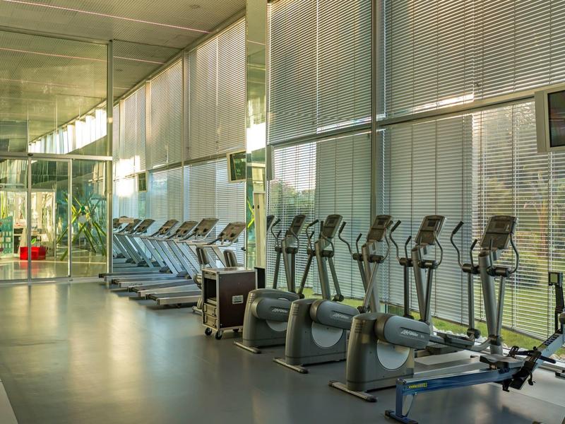 Moderne fitnessruimte met cardioapparatuur en grote glazen ramen.