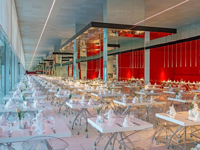 Modern restaurant met lange rijen van elegante tafels en stoelen, helder verlicht.