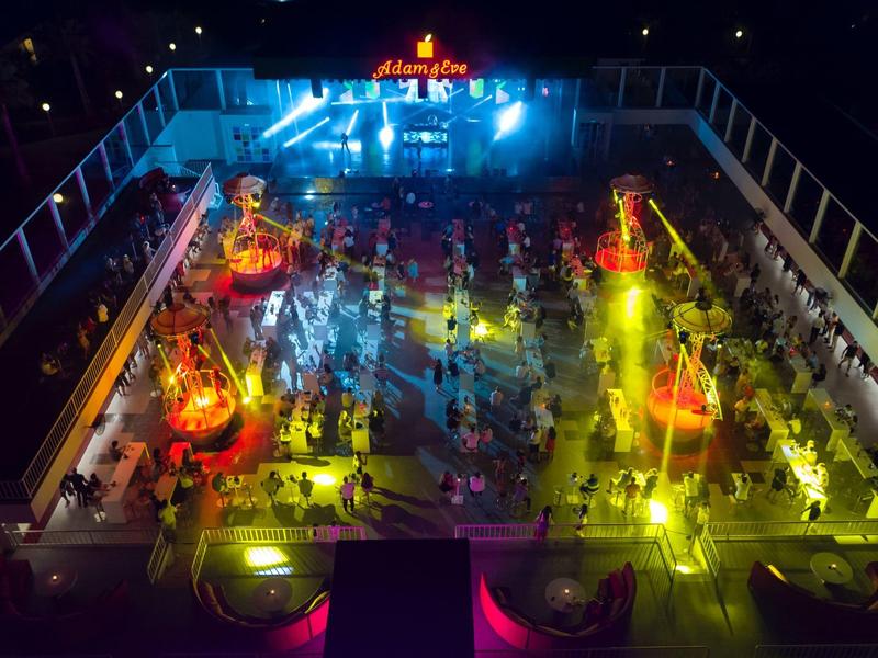 Kleurrijk verlicht carrousel op een druk nachtelijk festivalterrein in een pretpark.