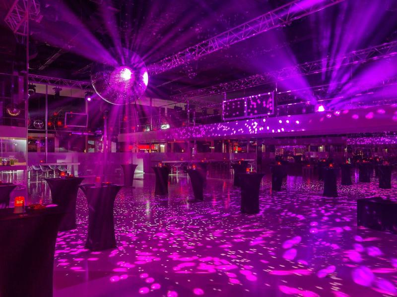 Grote evenementenruimte met paars licht en decoratieve discoballen