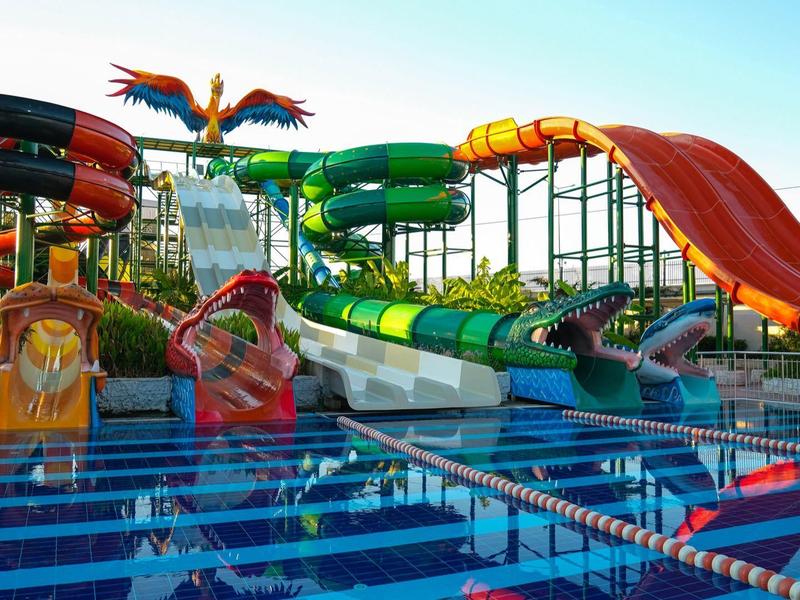 Toboggans aquatiques colorés à côté d'une piscine dans un parc aquatique ensoleillé.