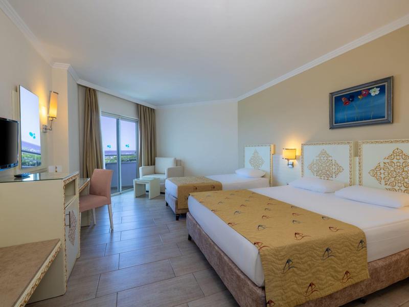 Chambre d'hôtel lumineuse avec deux lits, balcon et décoration moderne.