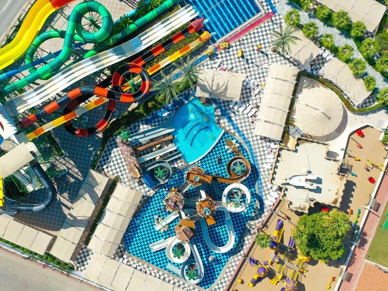 Vue aérienne d'un parc aquatique coloré avec des toboggans, des piscines et des espaces de détente.