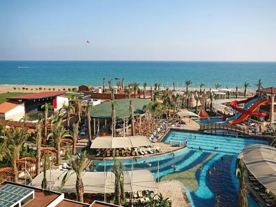 Grand complexe avec plusieurs piscines, toboggans aquatiques et vue sur la mer en arrière-plan.