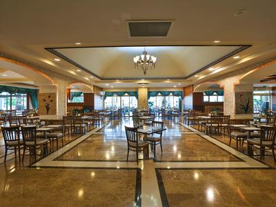 Grande salle à manger lumineuse d'hôtel avec de nombreuses chaises et tables en bois.