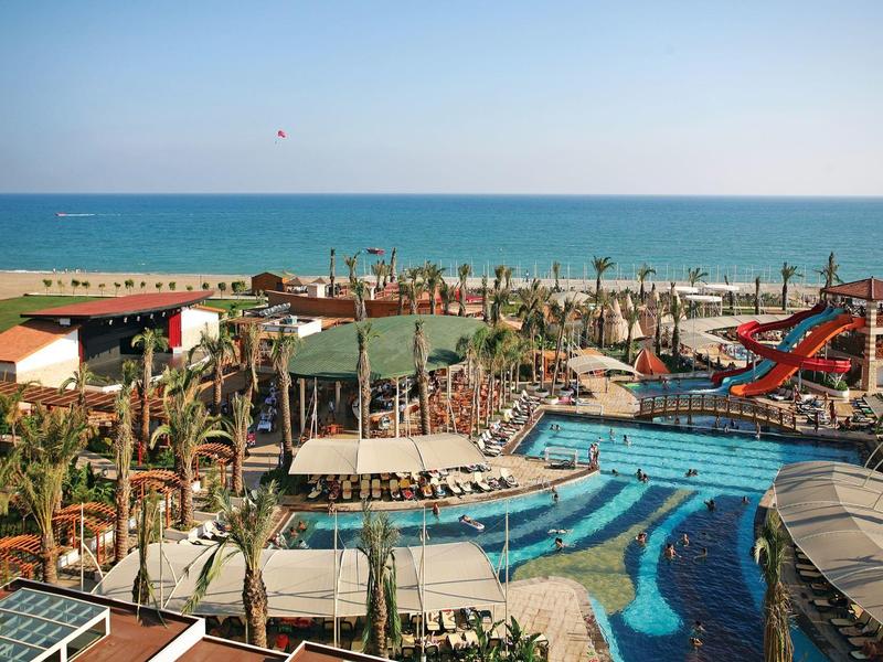 Grand complexe avec plusieurs piscines, toboggans aquatiques et vue sur la mer en arrière-plan.