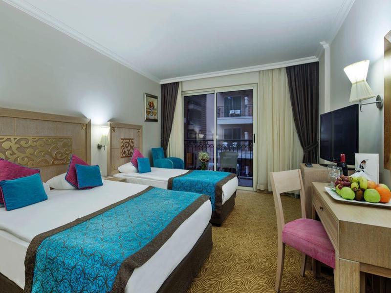 Chambre d'hôtel moderne avec lit double, bureau et grande fenêtre avec vue sur la ville.