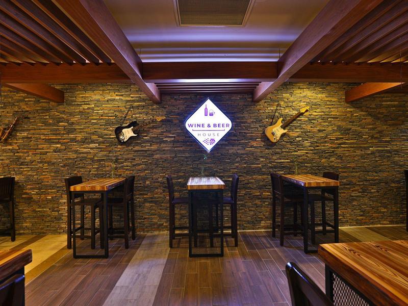 Intérieur chaleureux d'un bar avec tables en bois, chaises et éclairage doux.