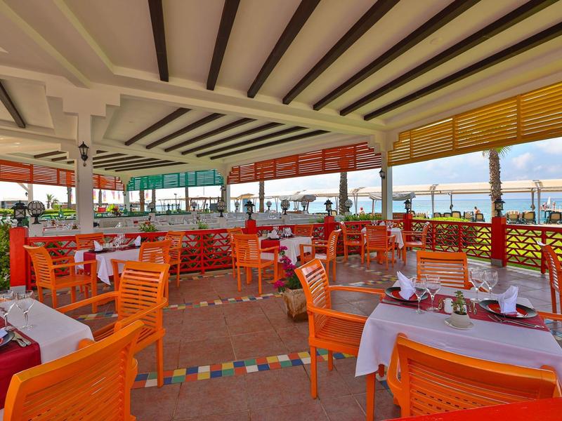 Restaurant lumineux et ouvert avec des chaises orange et vue sur la mer.