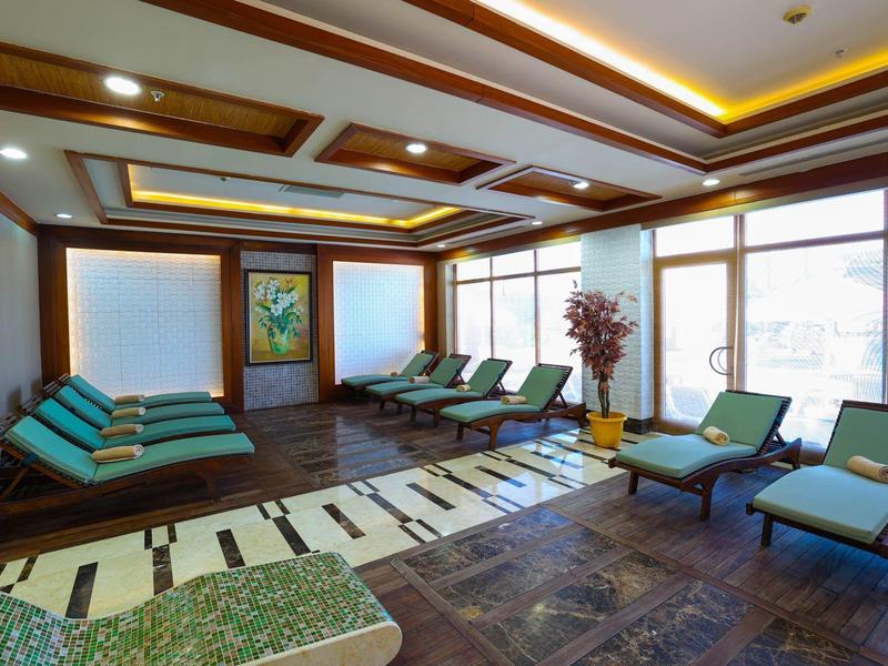 Salle de détente moderne avec chaises longues et tapis à motifs, lumineuse et accueillante.