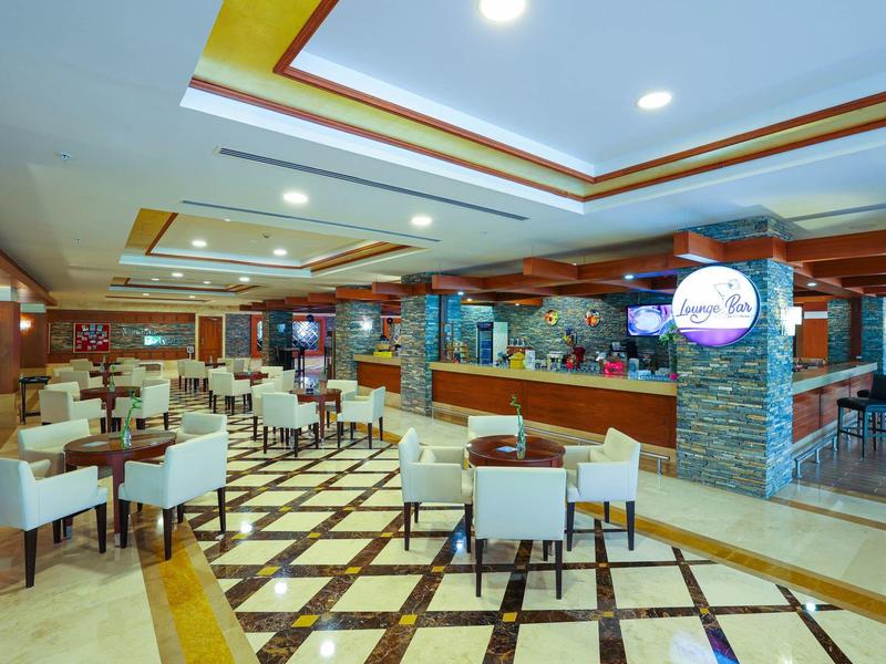 Grand espace de restaurant d'hôtel avec chaises élégantes, tables et sol à motifs.