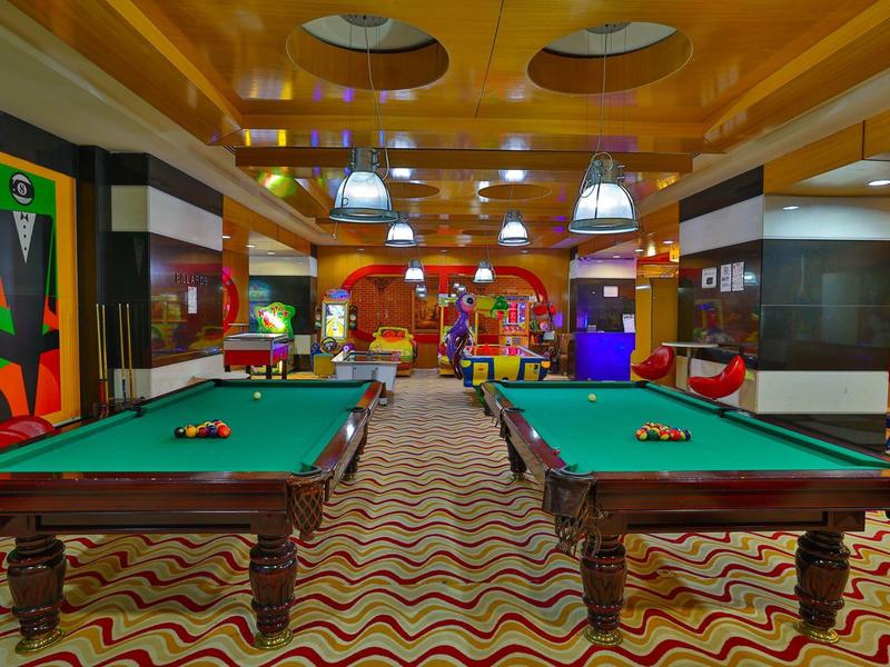 Deux tables de billard dans une salle de jeux colorée avec tapis à motifs et éclairage moderne.