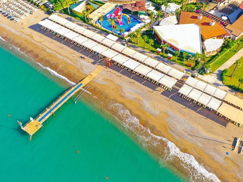Vue aérienne d'une plage avec une jetée, des parasols et des bars de plage au bord de la mer.