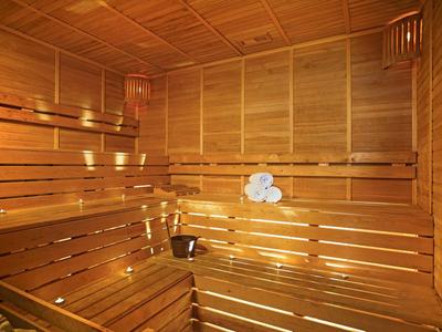 Innensauna aus hellem Holz mit Sitzbänken, Eimer und aufgerollten Handtüchern.