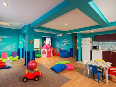 Bunter Kinderspielraum mit Spielzeug, Sitzkissen, Tischen, einer Spielecke und Küchenecke.