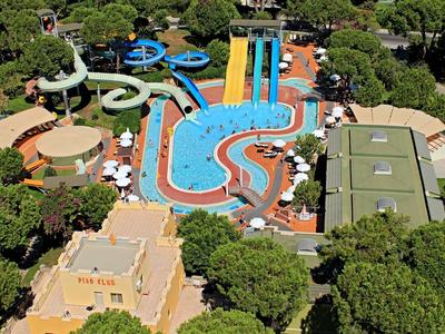 Wasserpark mit mehreren bunten Rutschen, blauem Pool und grünen Bäumen rundherum.