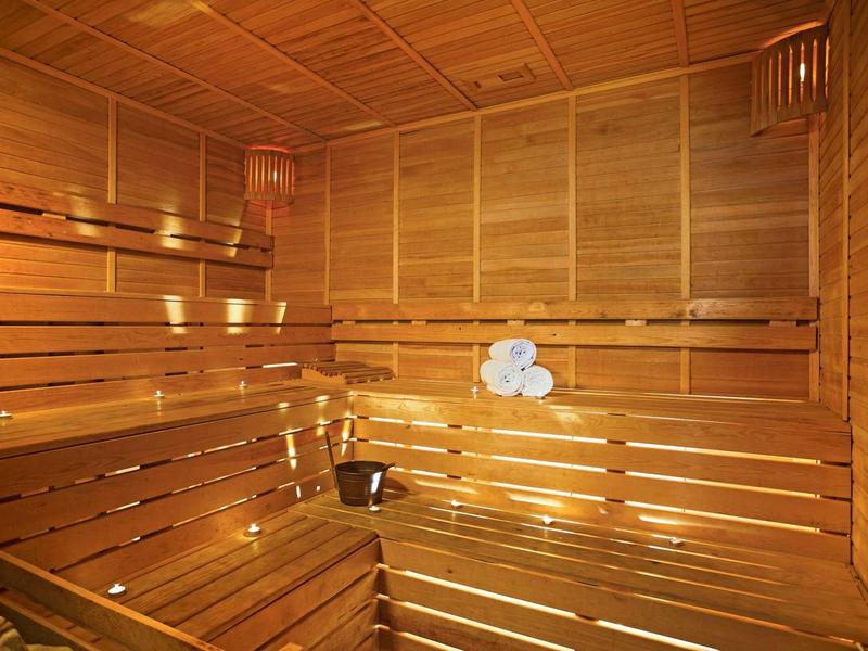 Innensauna aus hellem Holz mit Sitzbänken, Eimer und aufgerollten Handtüchern.