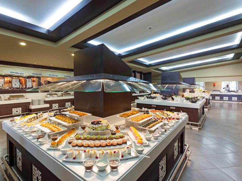 Großes Buffet mit verschiedenen kalten und warmen Speisen in hell beleuchtetem Speiseraum.