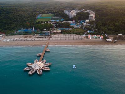 Aerial view of a beach resort with a stone pier extending into blue ocean water.