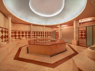 Round spa room with large columns, central pool, and cozy atmosphere.