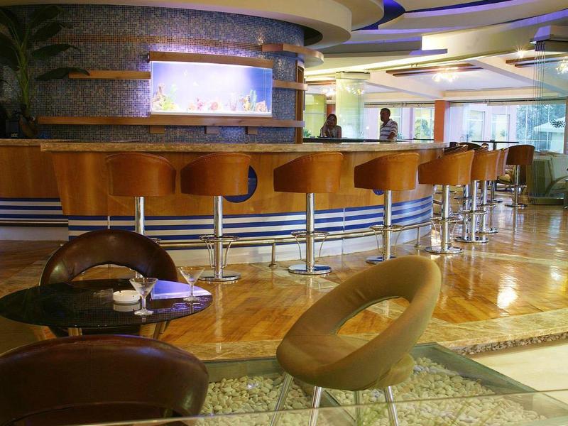 Modern hotel lobby with curved bar, colorful ceiling design, and cozy chairs.