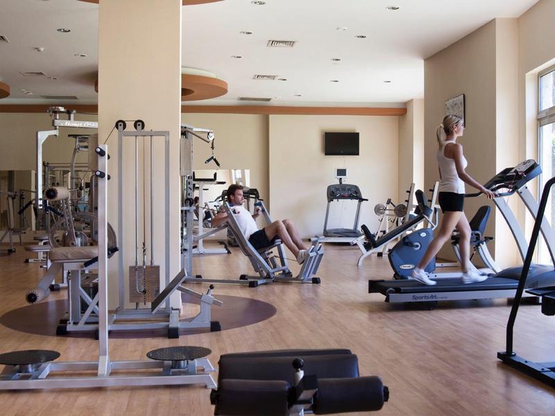 Modern gym with equipment and a man running on a treadmill in a bright room.
