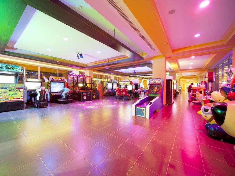 Bright, colorful arcade with various game machines and decorative lighting.