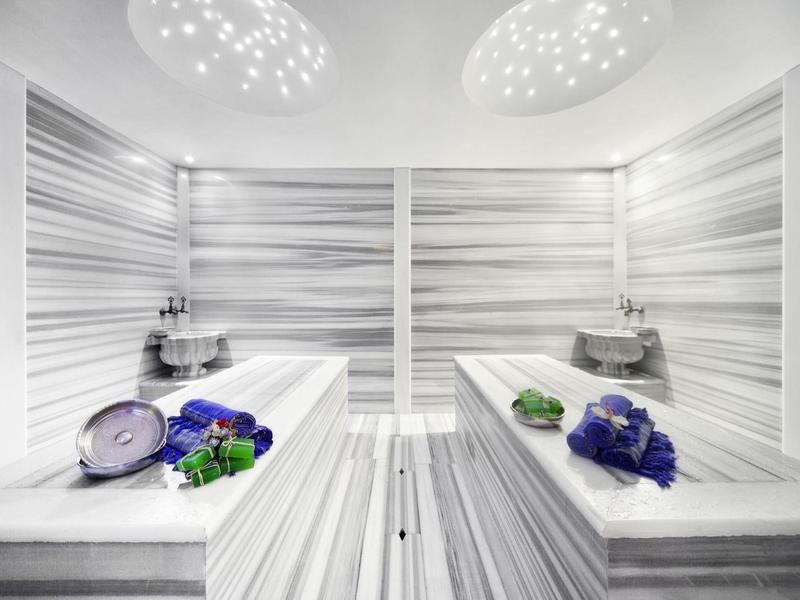 Brightly lit spa area with marble loungers and fresh towels.