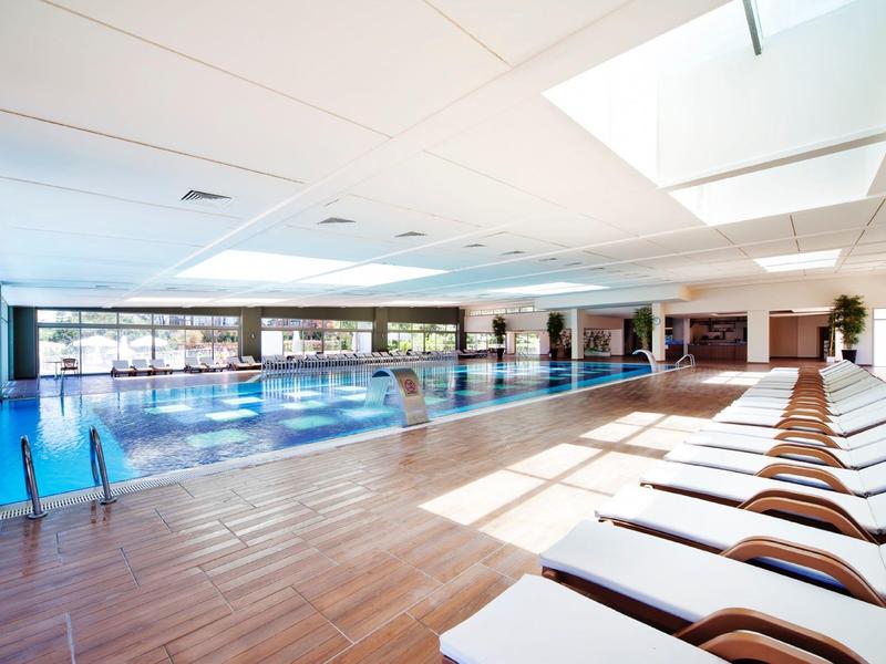 Large, bright indoor pool with lounge chairs and panoramic windows.