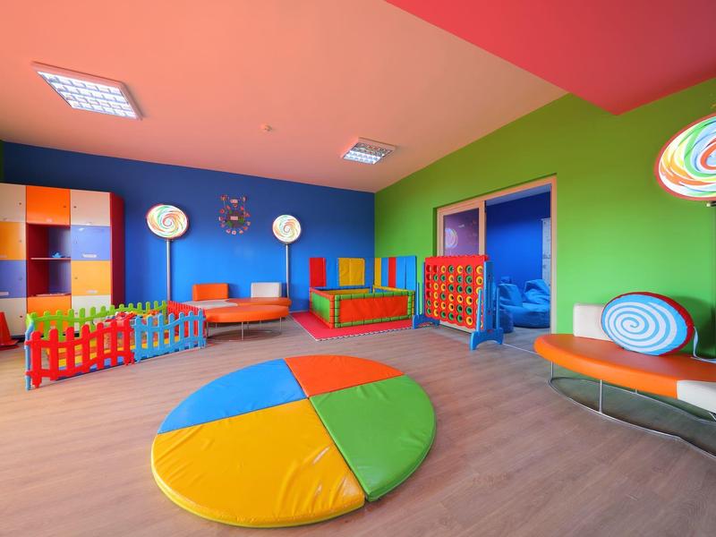 Colorful children's playroom with vibrant furniture, toys, and soft floor cushion.