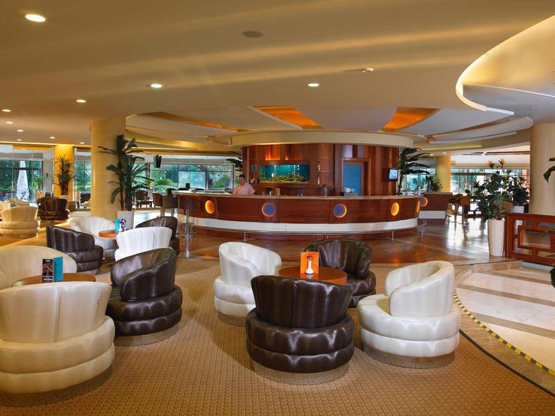 Cozy hotel lounge with round armchairs and a central bar bathed in warm light.