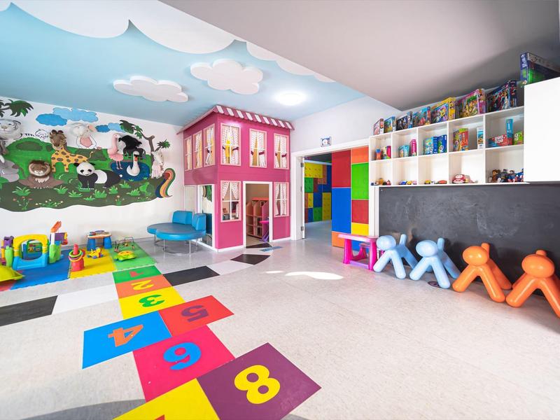 Colorful children's playroom with hopscotch, dollhouse, and mural