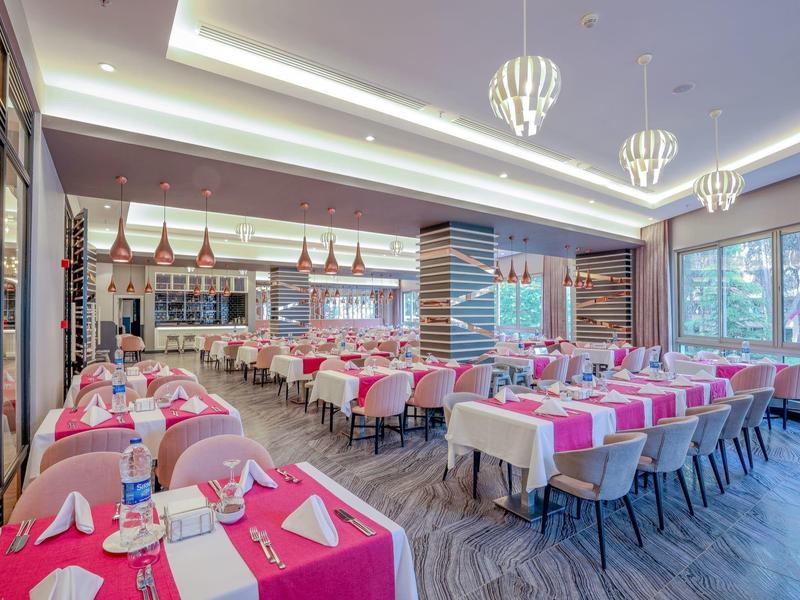 Modern restaurant with set tables and large windows allowing plenty of daylight.