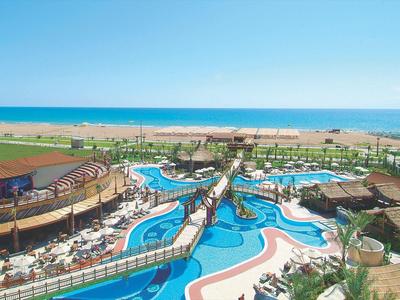 Grand complexe hôtelier avec piscines, plages, et vues sur la mer sous un ciel bleu clair.