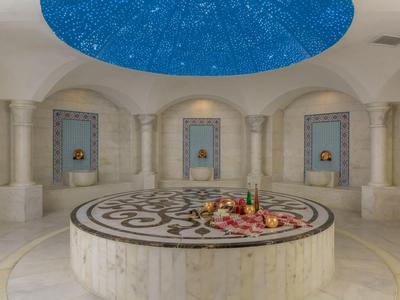 Intérieur d'un hammam avec un grand espace circulaire et un plafond étoilé.