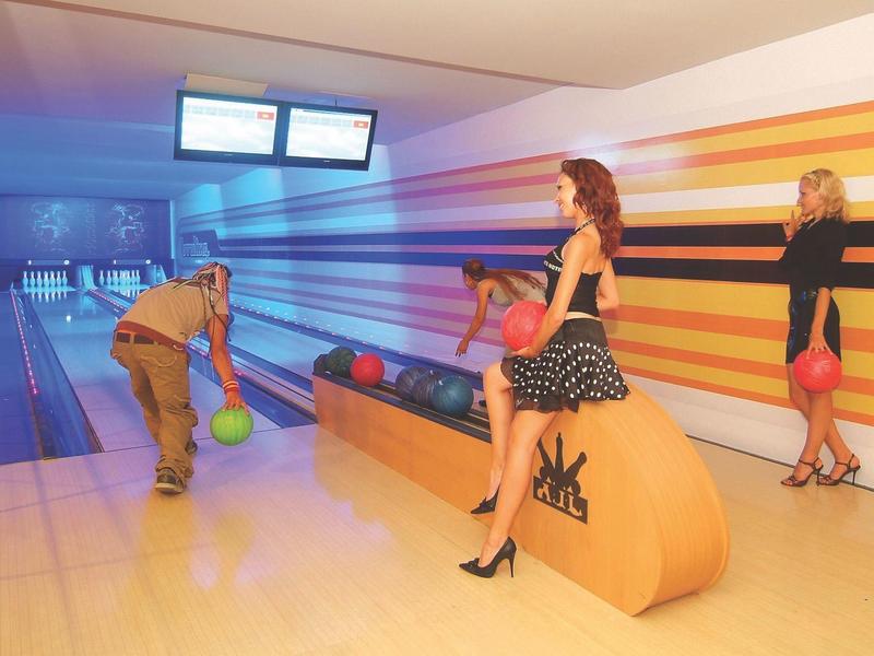 Personnes jouant au bowling dans une salle colorée avec des rayures et des chaussures de bowling.