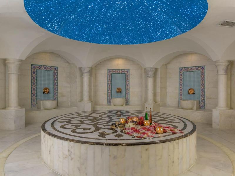 Intérieur d'un hammam avec un grand espace circulaire et un plafond étoilé.