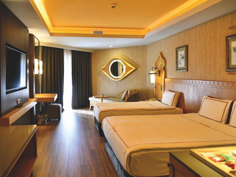 Chambre d'hôtel élégante avec lits doubles, décor moderne et lumière ambiante chaude.