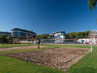 Un campo da beach volley con rete davanti a edifici di hotel sotto un cielo azzurro.