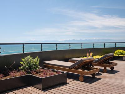 Deux chaises longues sur une terrasse en bois avec vue sur la mer bleue et le ciel.