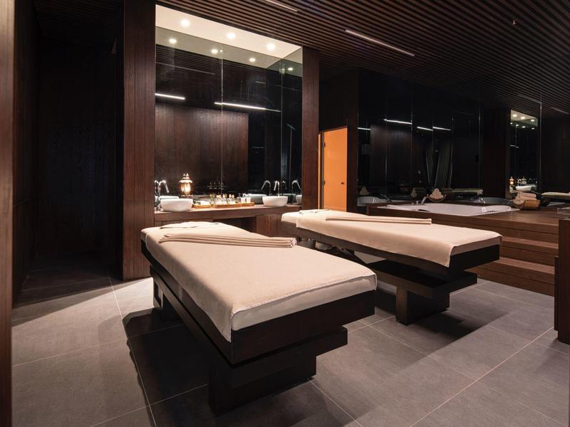 Sala moderna de spa o tratamiento con dos camillas y detalles cálidos de madera.