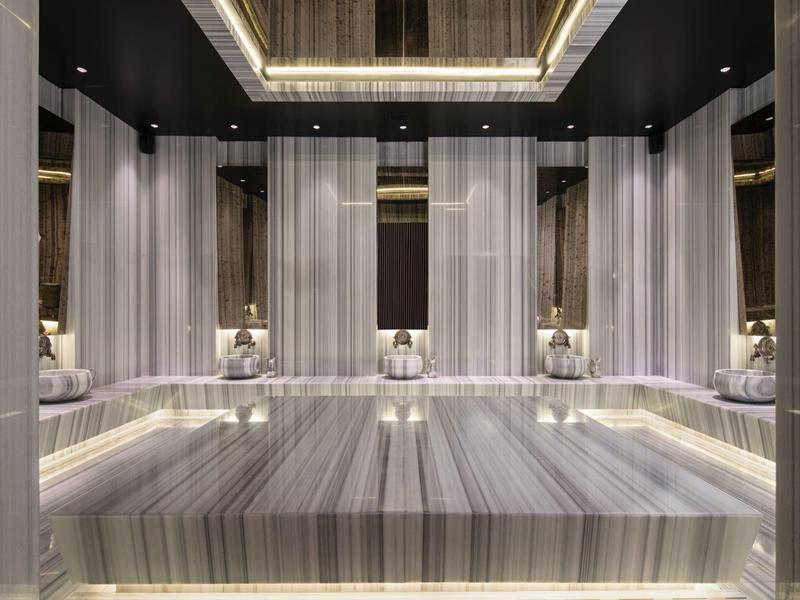 Spa lujoso revestido en mármol con iluminación suave y lámparas elegantes.