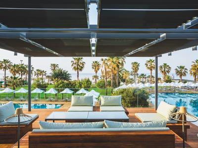 Moderner Außenbereich mit bequemen Sofas, Palmen und einem blauen Pool im Hintergrund.