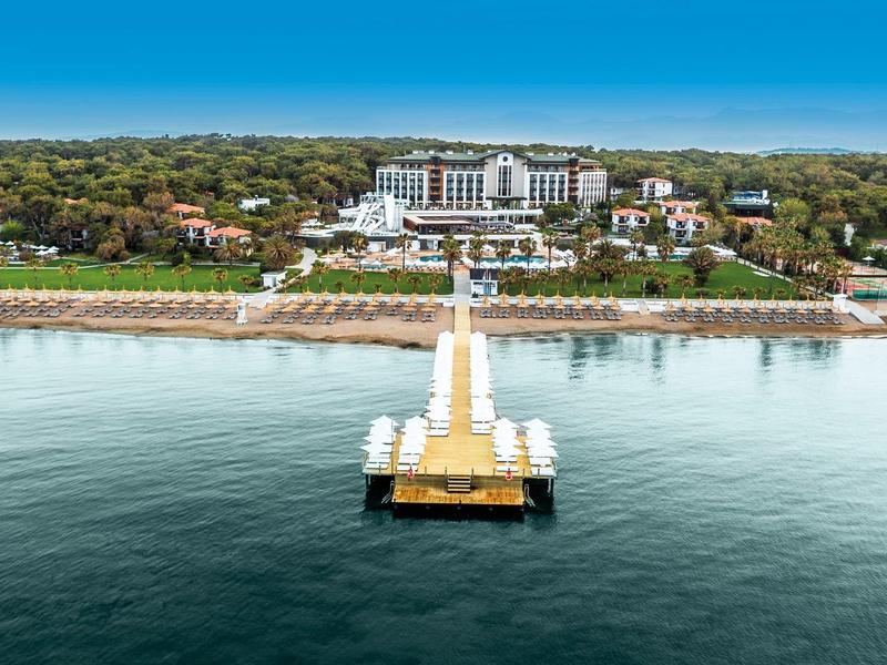 Velký hotel s dlouhým molem vedoucím do klidné vody a pláží s deštníky.