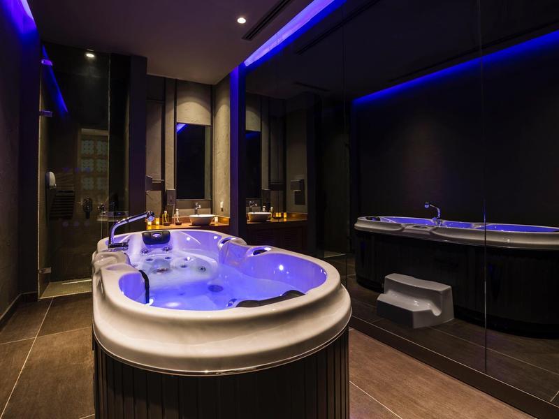 Luxusní vnitřní spa s osvětleným jacuzzi a tmavým ambientním osvětlením.