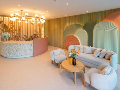 Área de salón moderna de hotel con paneles de pared coloridos y mobiliario cómodo.