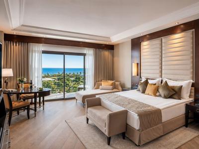 Camera d'hotel con letto matrimoniale, zona salotto e vista mare dalla finestra.