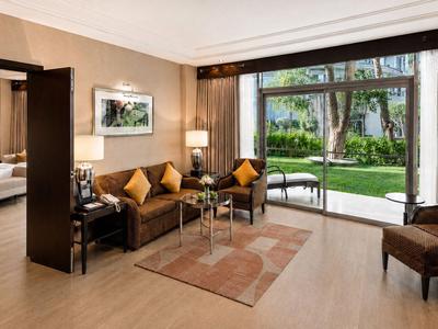 Zona soggiorno d'hotel moderna con divano, tavolo e ampia finestra con vista sul giardino.