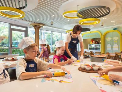 Kinder lernen backen in einem hellen, modernen Kochstudio mit runden Lampen.